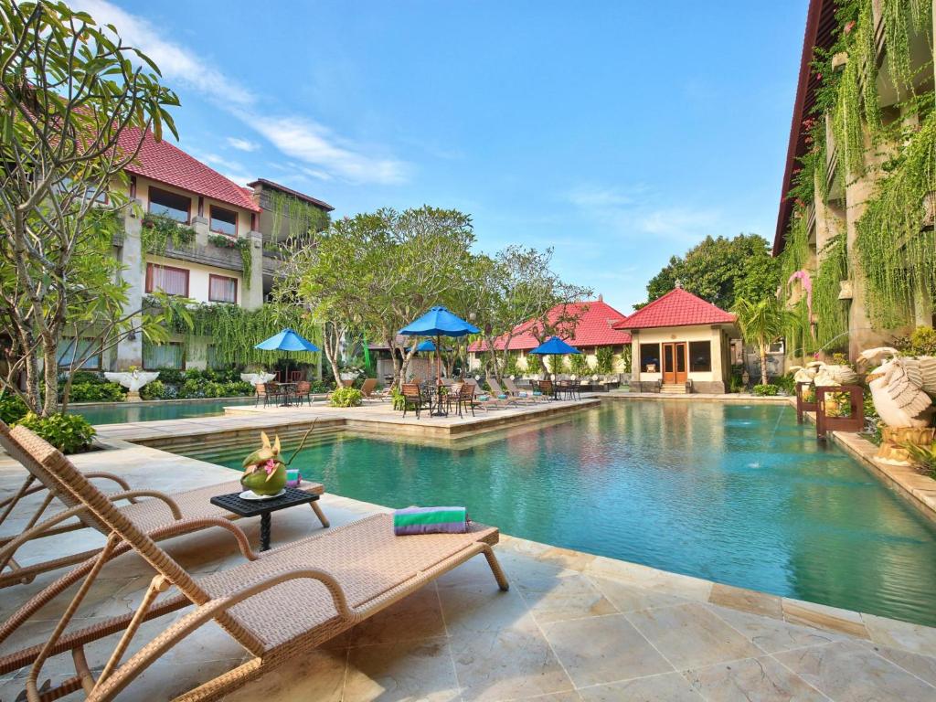 uma piscina num resort com cadeiras e mesas em The Grand Bali Nusa Dua em Nusa Dua