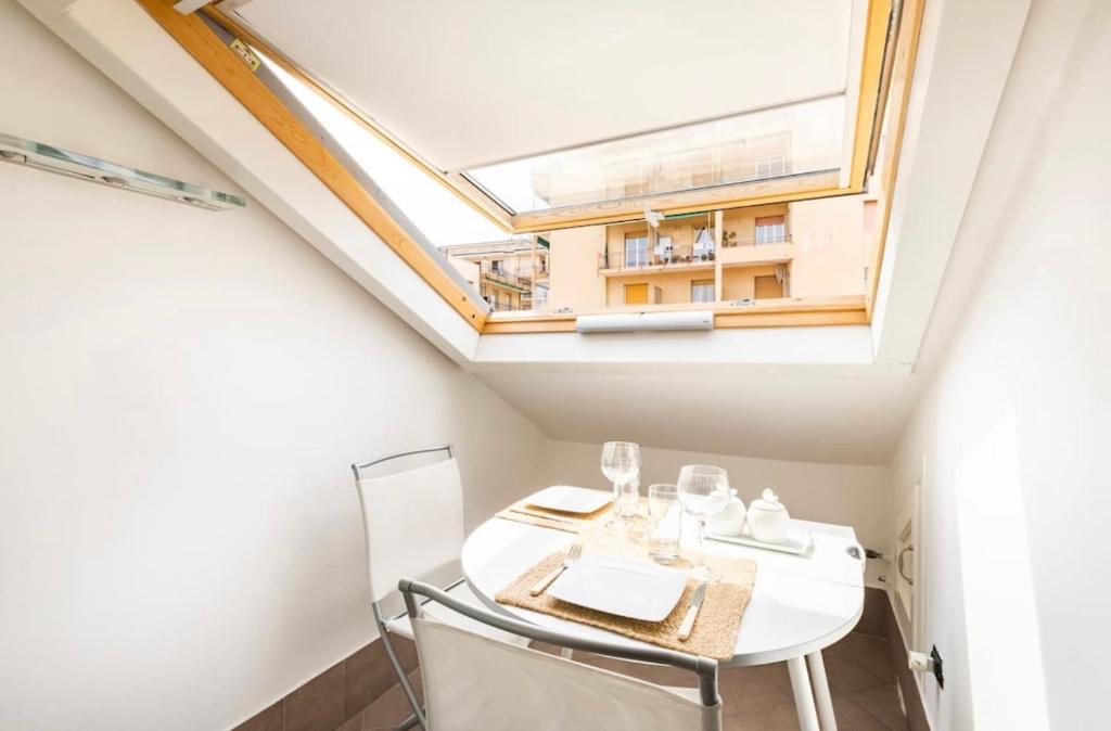 a dining room with a skylight and a white table and chairs at Fuga romantica - Mansarda chic con box privato & mare a 150m in Loano