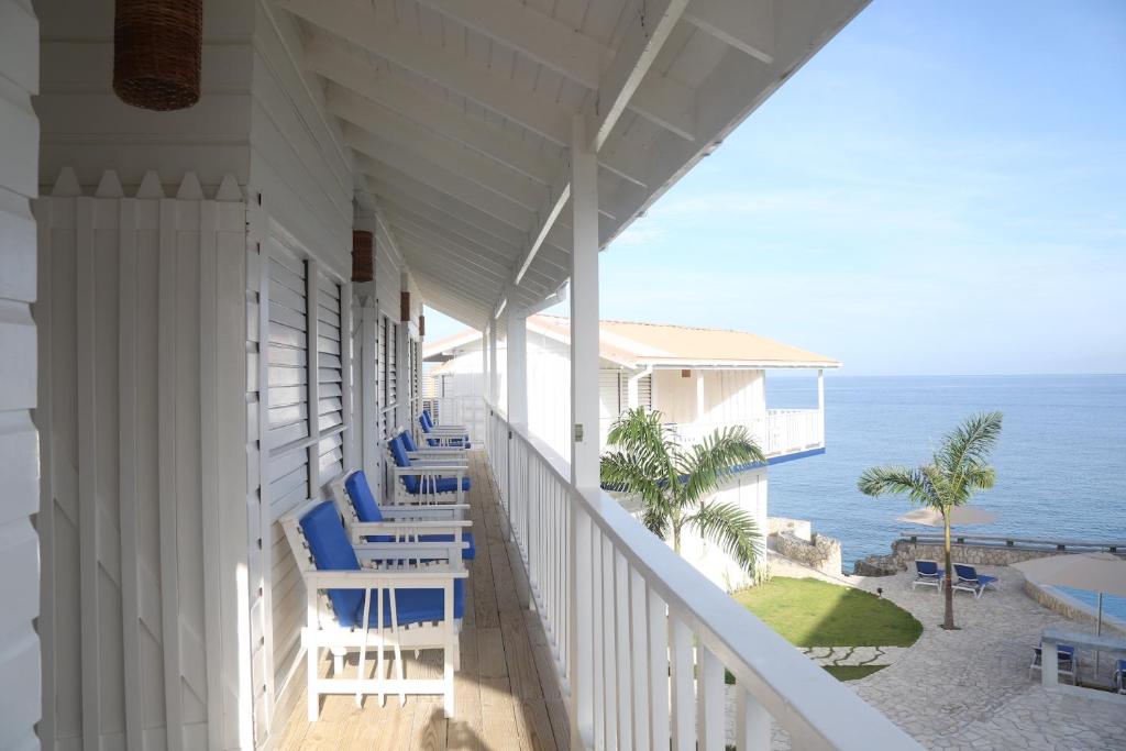 uma varanda de uma casa com cadeiras e o oceano em Begona Cliff Hotel em Negril