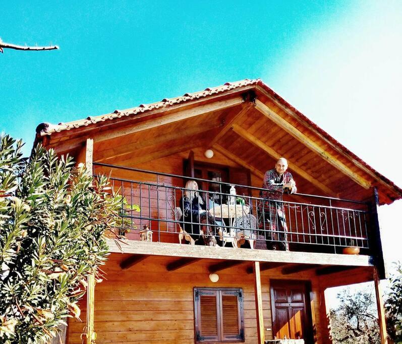 duas pessoas e dois cães numa varanda de uma casa em Olive Grove Chalet em Lepanto