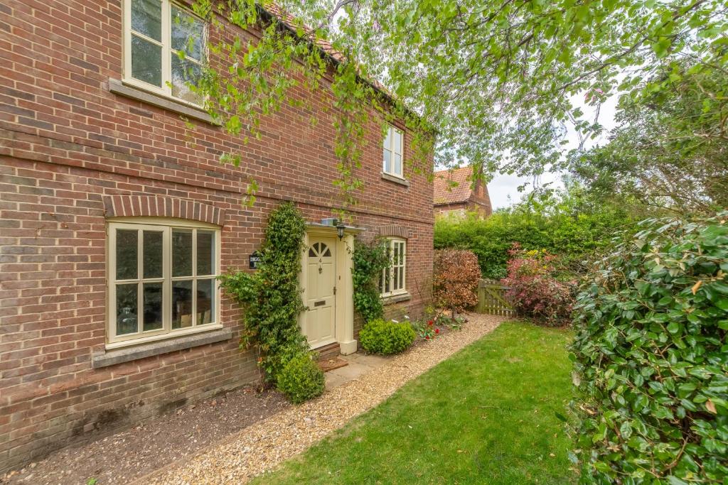 a brick house with a white door and a yard at Diggers Rest in Burnham Market