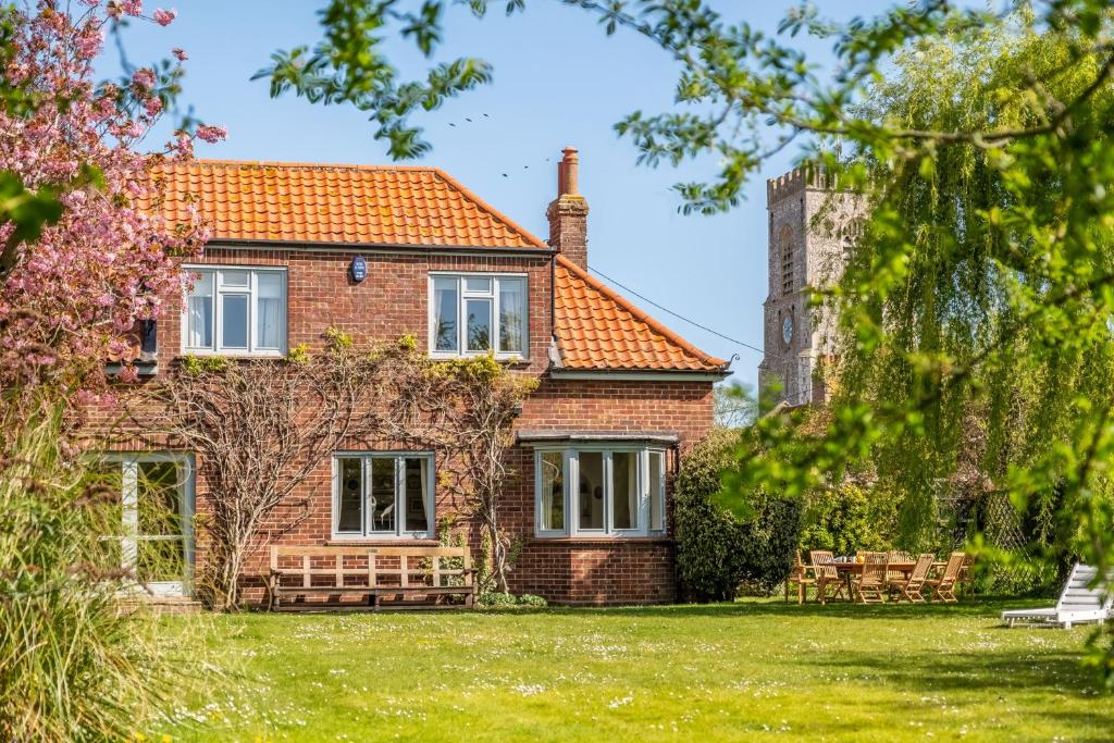 a brick house with a tower in the background at Orchard Cottage W in Wells next the Sea
