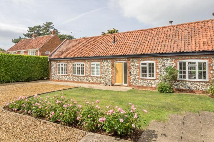 una casa di mattoni con una porta gialla e un cortile di Westgate Cottage T 4 a Thornham