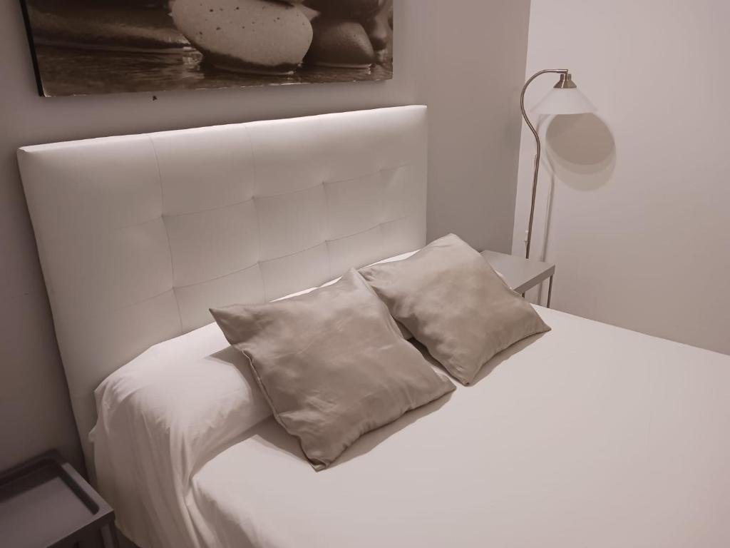 un letto bianco con due cuscini sopra di MAR2 - Las columnas de Adriano a Siviglia