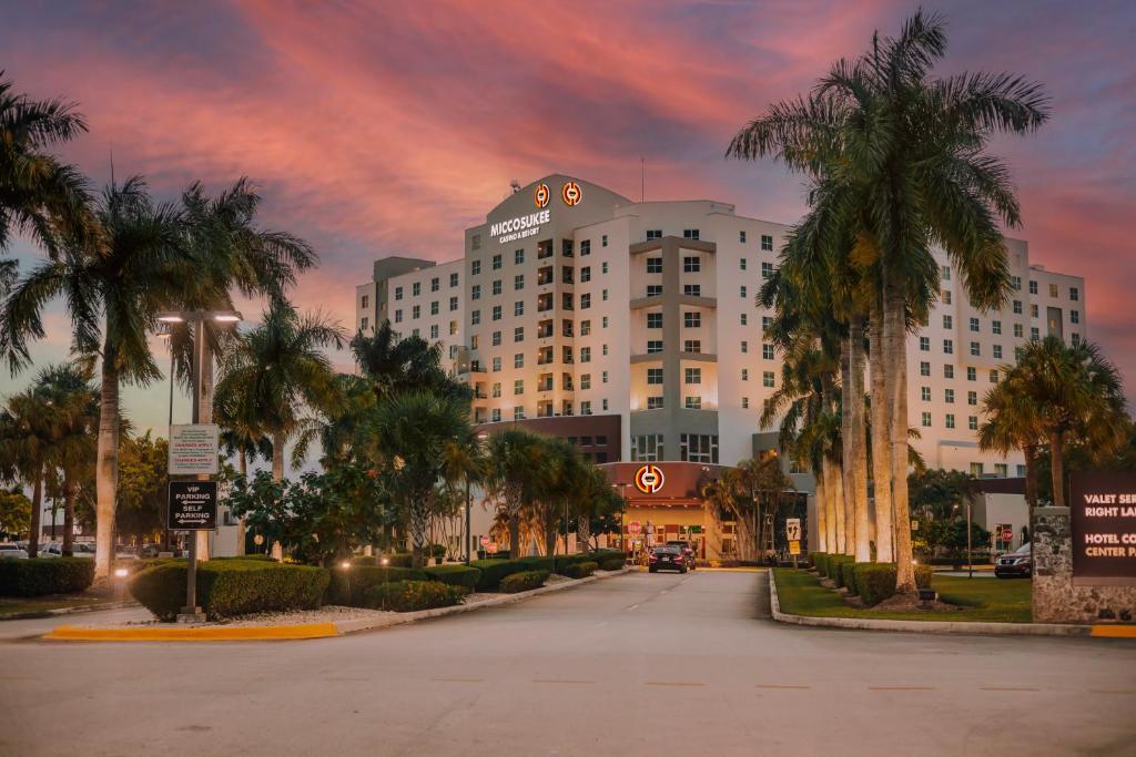 a large white building with palm trees on a street at Miccosukee Casino & Resort in Miami