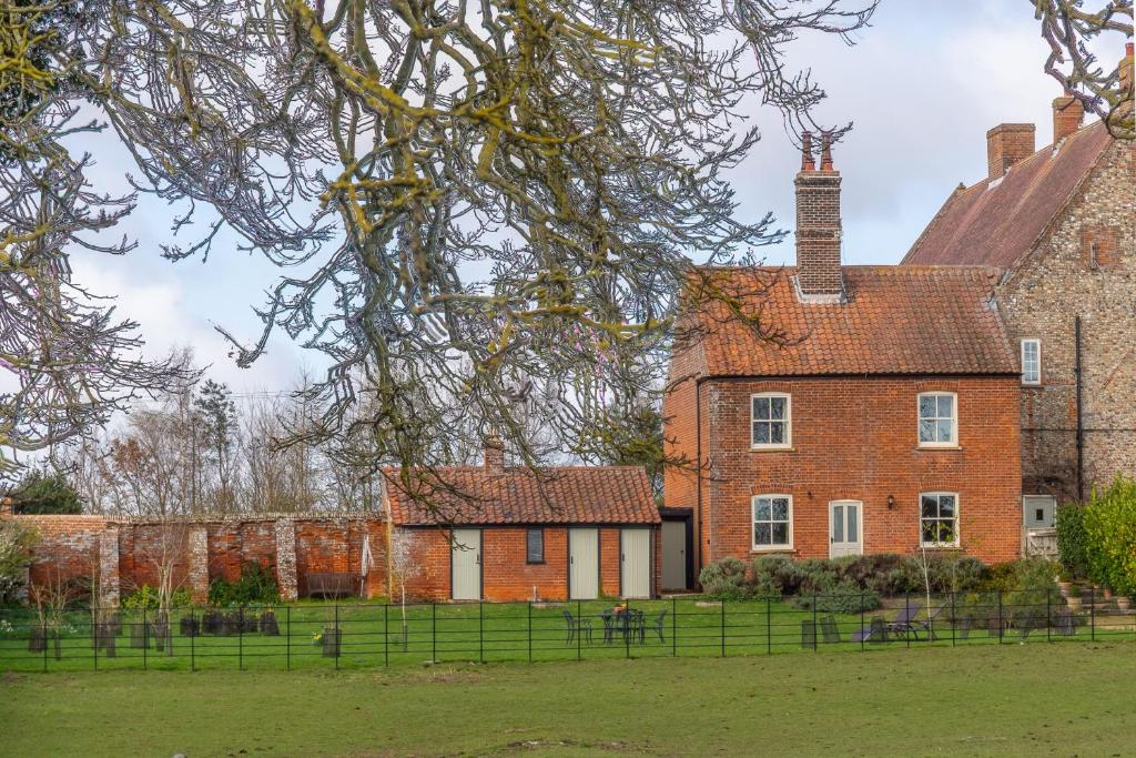 an old brick house with a grass yard in front of it at Ludham Hall Cottage in Ludham