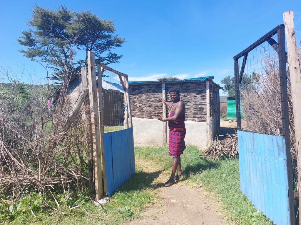 un homme debout devant une porte dans l'établissement Maasai homestay camping, à Sekenani