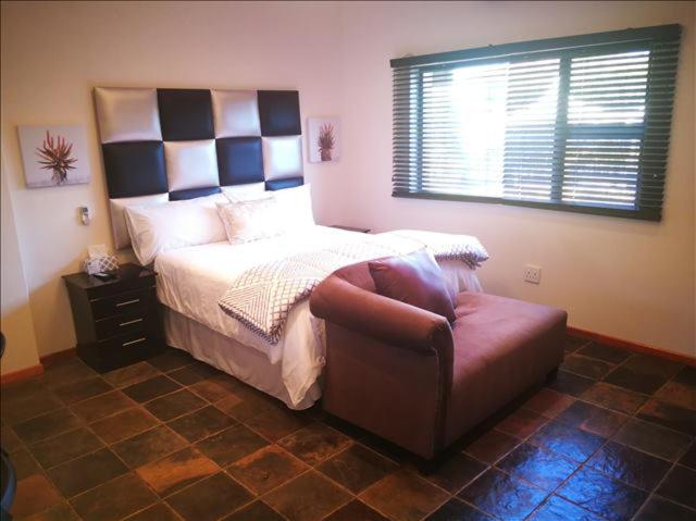 a bedroom with a bed and a chair and a window at Sleep Haven in Johannesburg