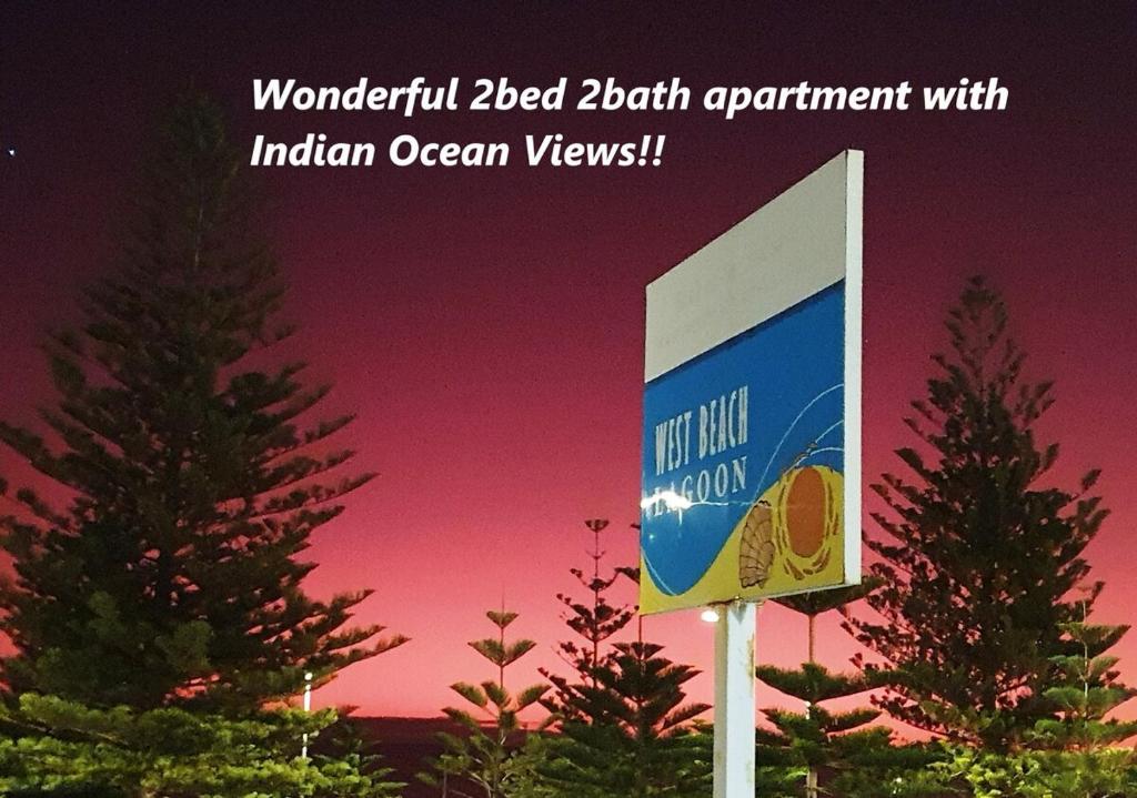 una señal frente a dos árboles con una puesta de sol en Wonderful 2bed 2bath Apartment With Ocean Views ! en Perth