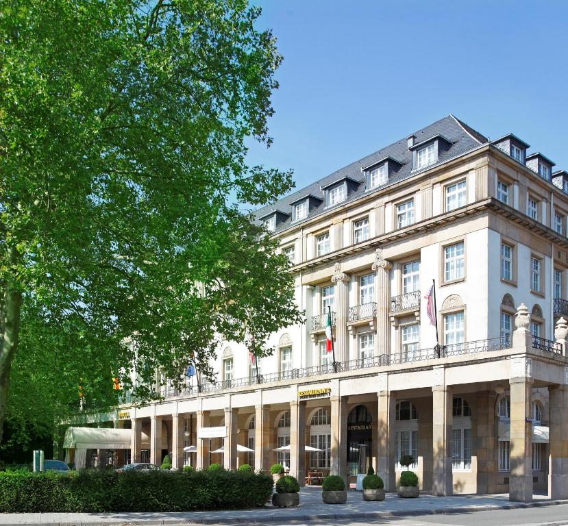 ein großes weißes Gebäude mit einem Baum davor in der Unterkunft Schlosshotel Karlsruhe in Karlsruhe