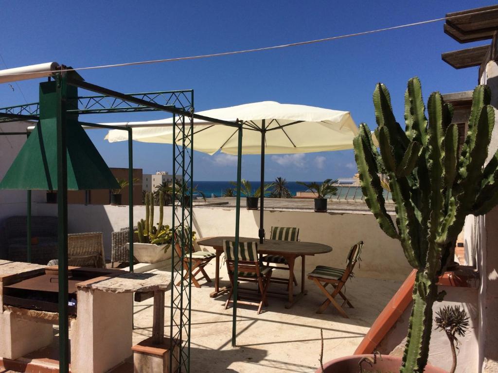 eine Terrasse mit einem Tisch, einem Sonnenschirm und einem Kaktus in der Unterkunft Alla Busiata in Trapani
