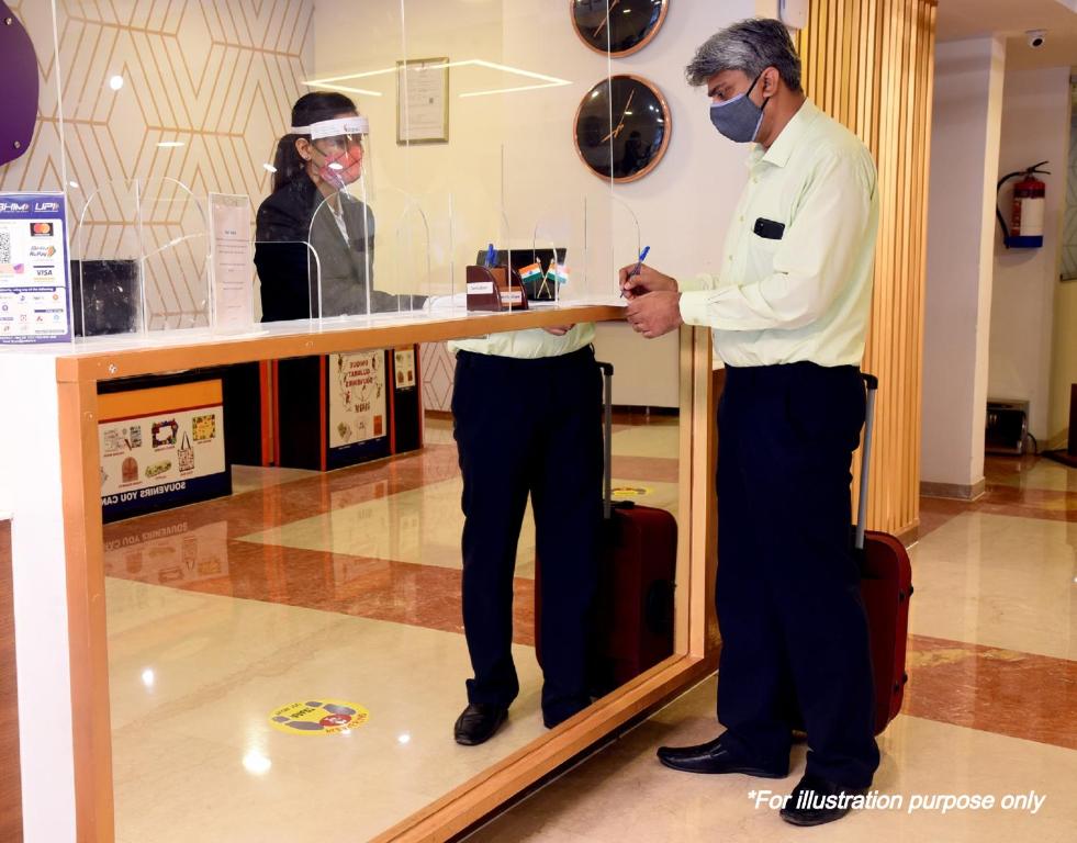 a man wearing a mask standing in front of a mirror at OYO 70254 Billu Hotel in Manesar