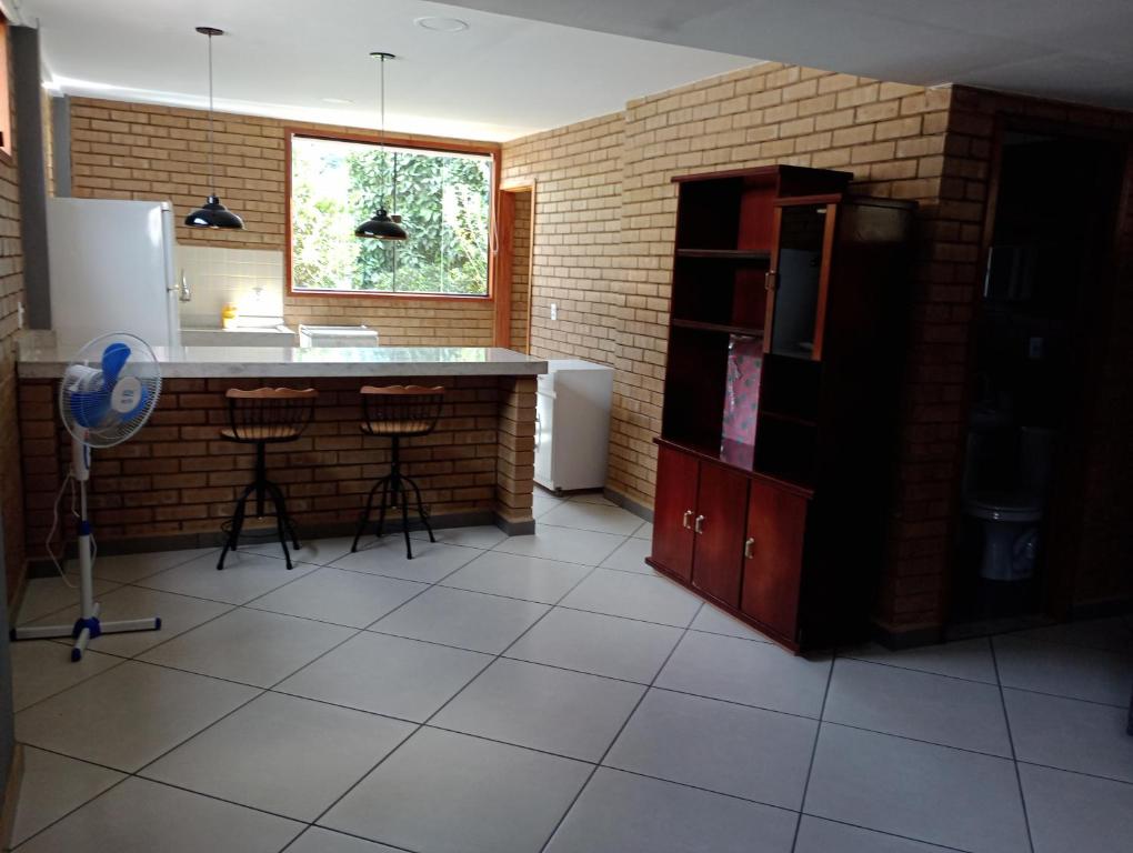 une cuisine avec un évier et un comptoir avec des tabourets dans l'établissement Casa em Duas Barras a 45 minutos de Nova Friburgo, à Duas Barras
