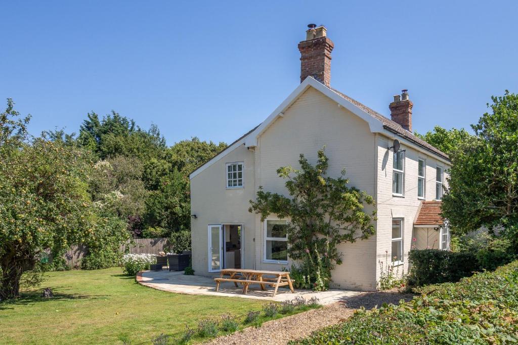 a white house with a picnic bench in front of it at Brook House in Briston