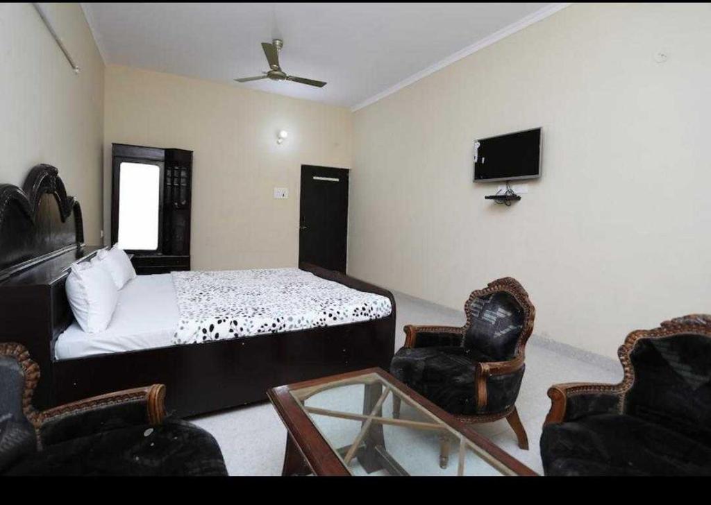 a bedroom with a bed and a tv and chairs at POP Hotel Amrit Castle 2 in Morādābād
