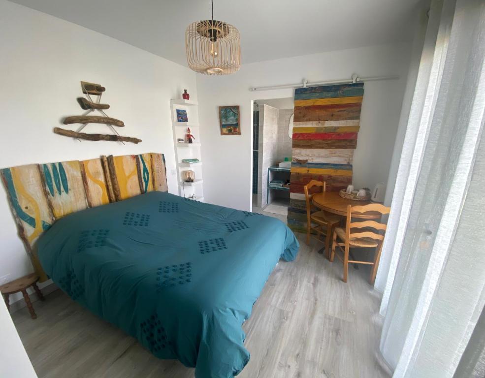 um quarto com uma cama azul e uma mesa em La chambre de Séraphine em Biscarrosse