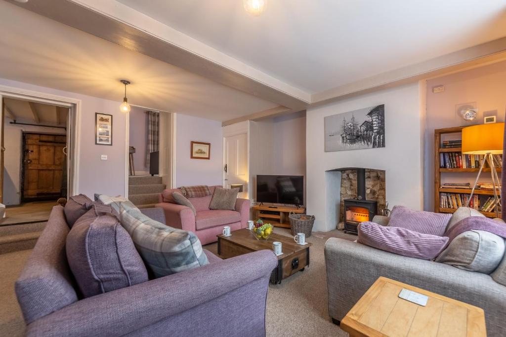 a living room with two couches and a fireplace at Greyhound Cottage in Sculthorpe