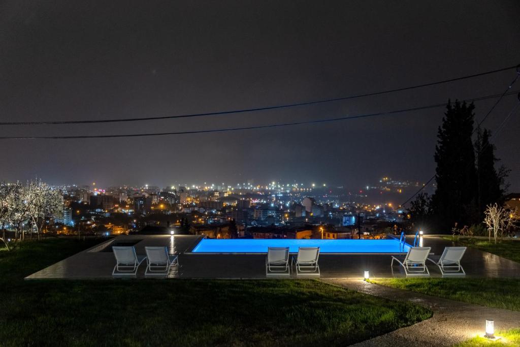 a pool at night with a view of the city at Uphill Glavanovic Villas in Bar
