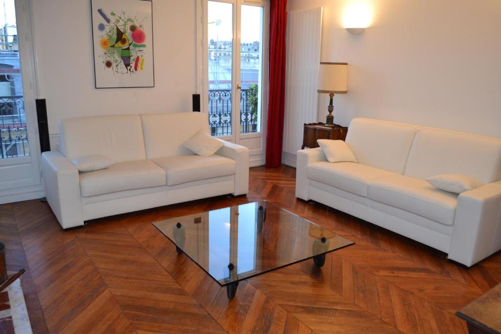 sala de estar con 2 sofás blancos y mesa de cristal en Appartement moulin rouge II en París