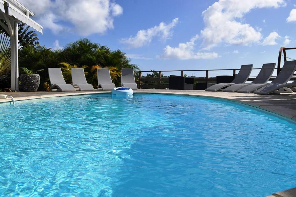 uma grande piscina com cadeiras ao redor em La Villa Cocoon prestige et vue mer em Sainte-Luce