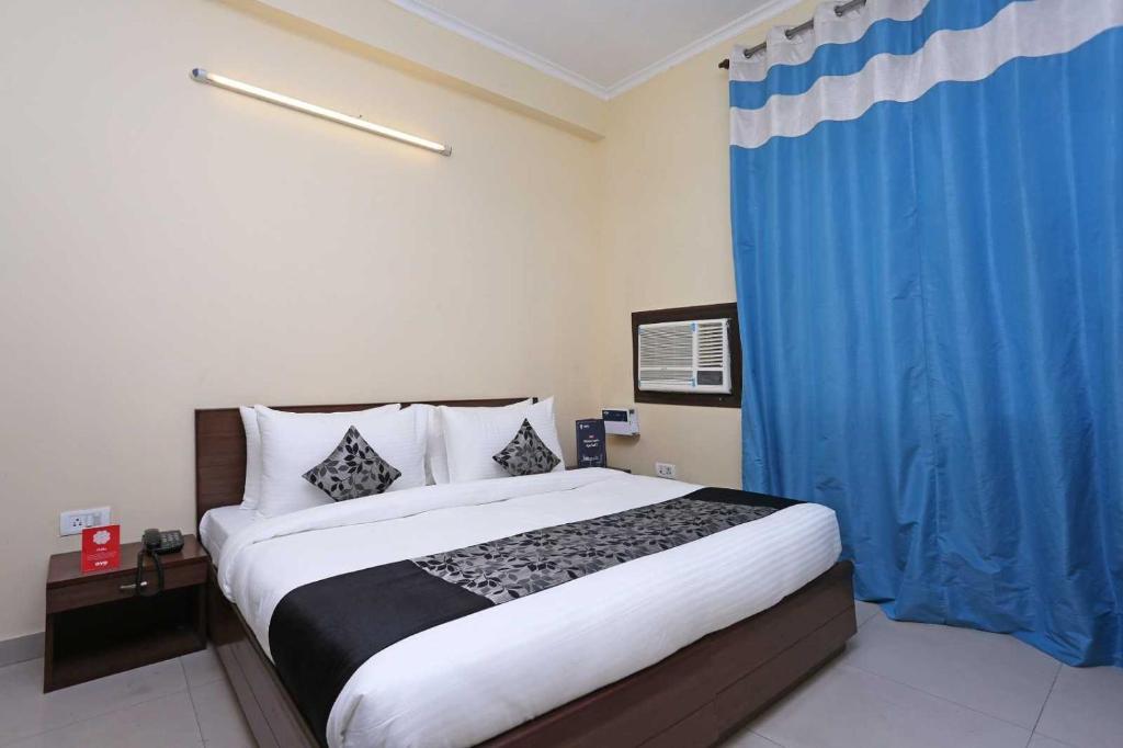 een slaapkamer met een groot bed en een blauw gordijn bij Flagship Om Tara in McLeod Ganj