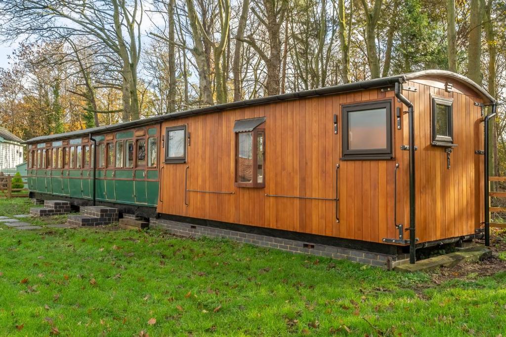 a wooden train car sitting in a field at The Railway Carriage in Melton Constable