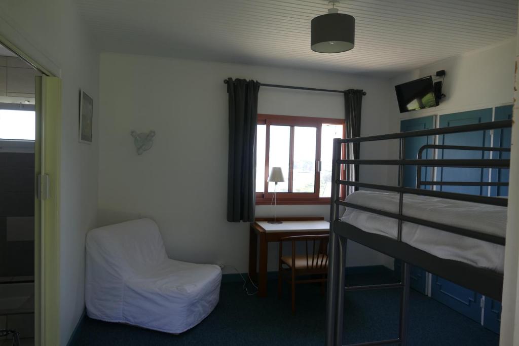 a dorm room with a bunk bed and a chair at Kerbugalic Grand gîte, Magnifique vue mer in Trévou-Tréguignec