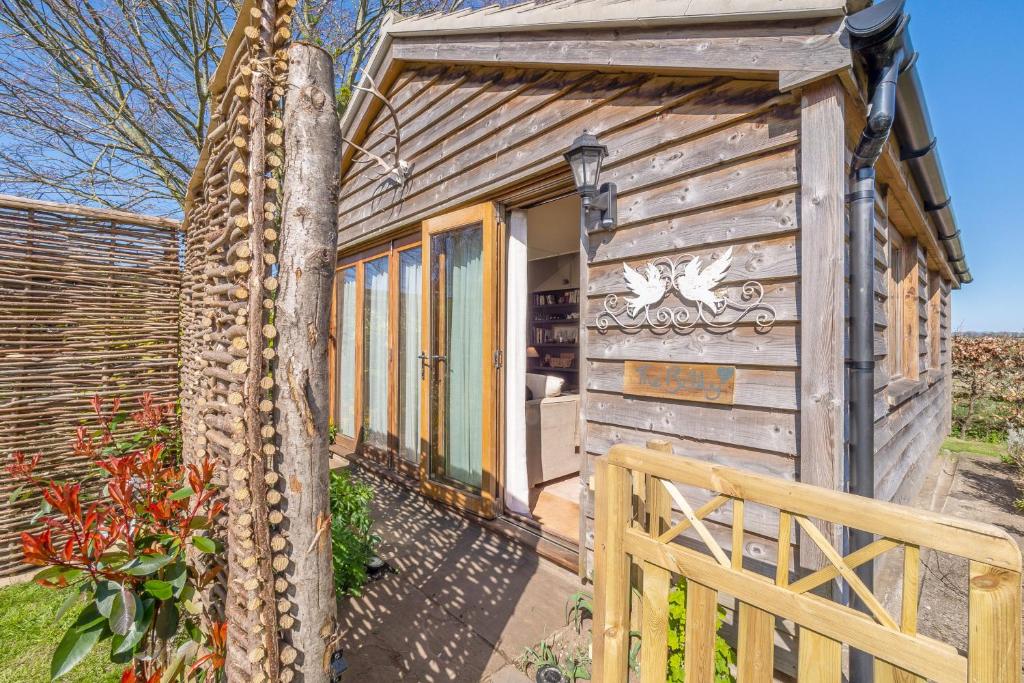 een tiny house met een houten deur en een hek bij The Bothy in Ringstead