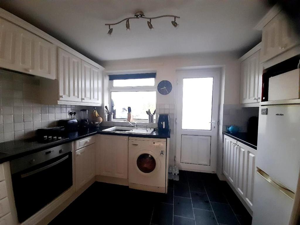 a kitchen with a sink and a washing machine at Spacious Bungalow in Pinxton