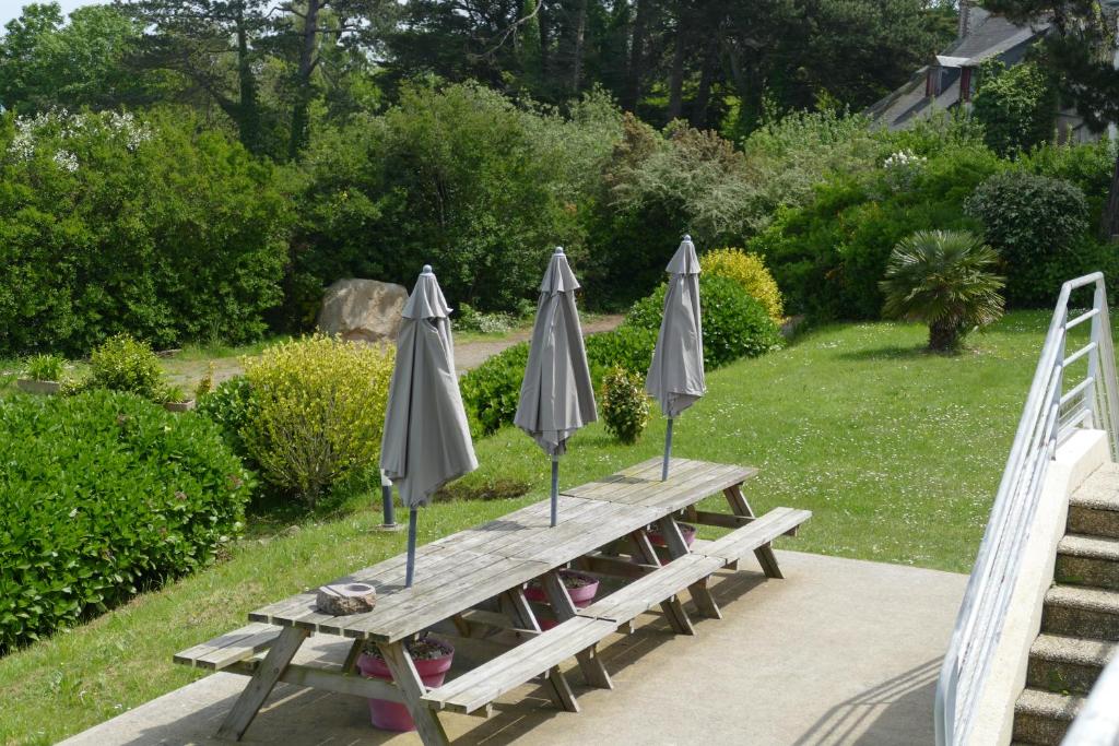 a wooden picnic table with two umbrellas on it at Kerbugalic Grand gîte, Magnifique vue mer in Trévou-Tréguignec