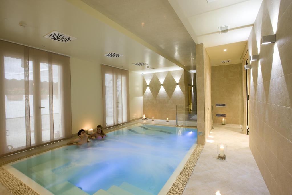 dos personas sentadas en una piscina en un edificio en Hotel Consuelo, en Riccione
