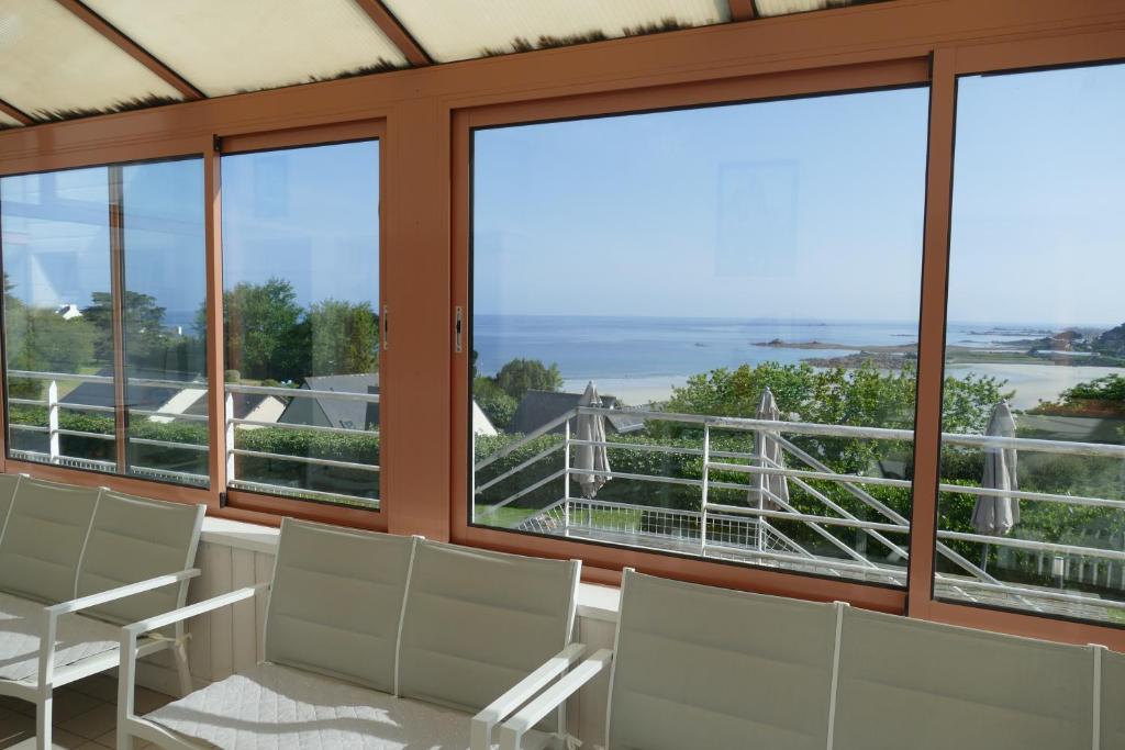 a room with windows and chairs and a view of the ocean at Kerbugalic Grand gîte, Magnifique vue mer in Trévou-Tréguignec