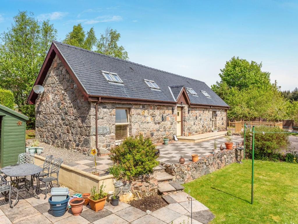 a stone house with a garden and a patio at Fyvie Cottage in Banavie