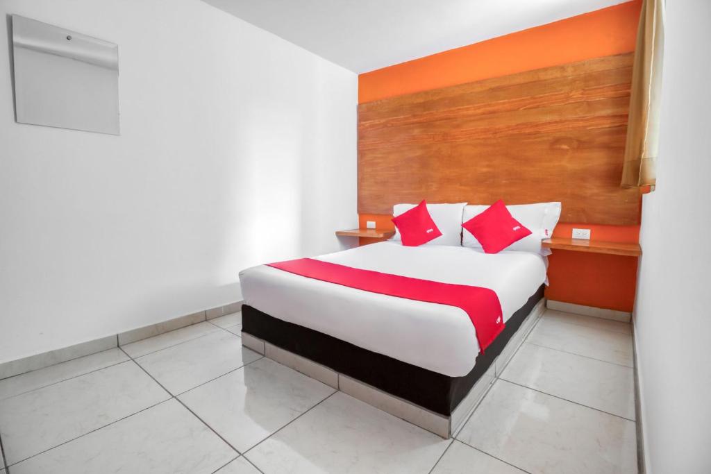 Habitación de hotel con cama con almohadas rojas en OYO Hotel Familiar Tollan en Cholula