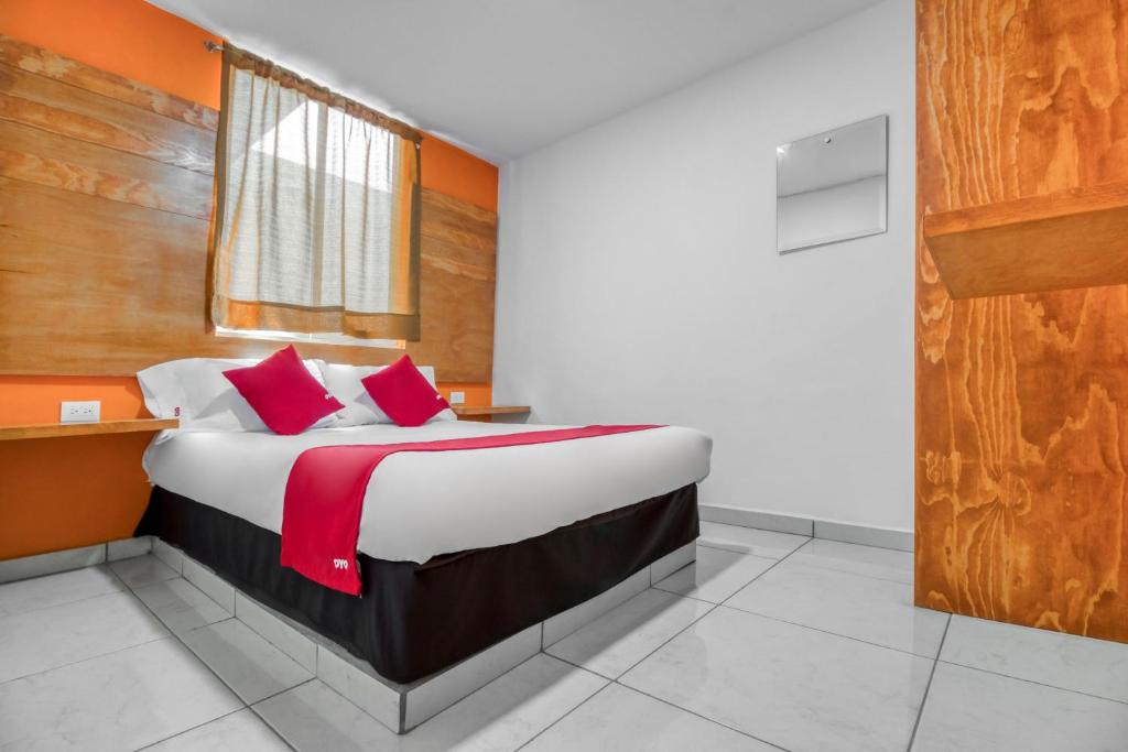 OYO Hotel Familiar Tollan في تشولولا: غرفة نوم بسرير كبير ومخدات حمراء