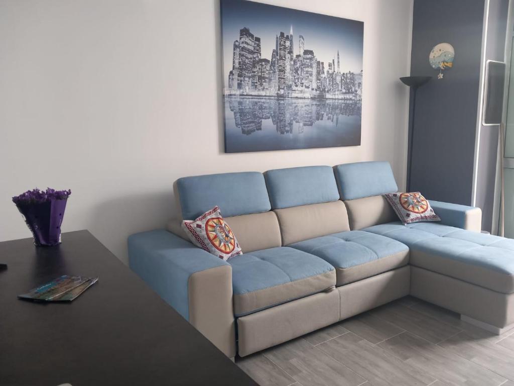 ein Wohnzimmer mit einem blauen Sofa und einem Tisch in der Unterkunft ATTICO ARDESIA in Cefalú