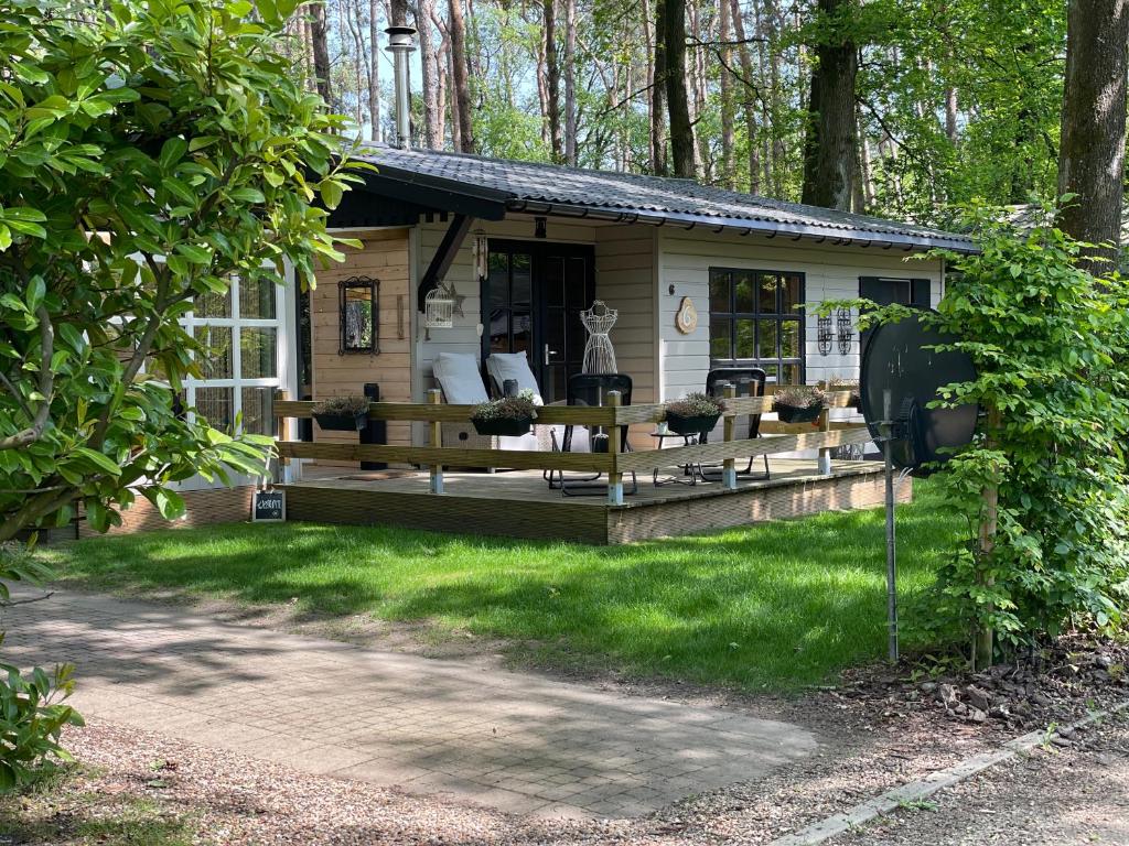 a house with a porch in the woods at Chalet Sint-Hubertus Deluxe in Zutendaal