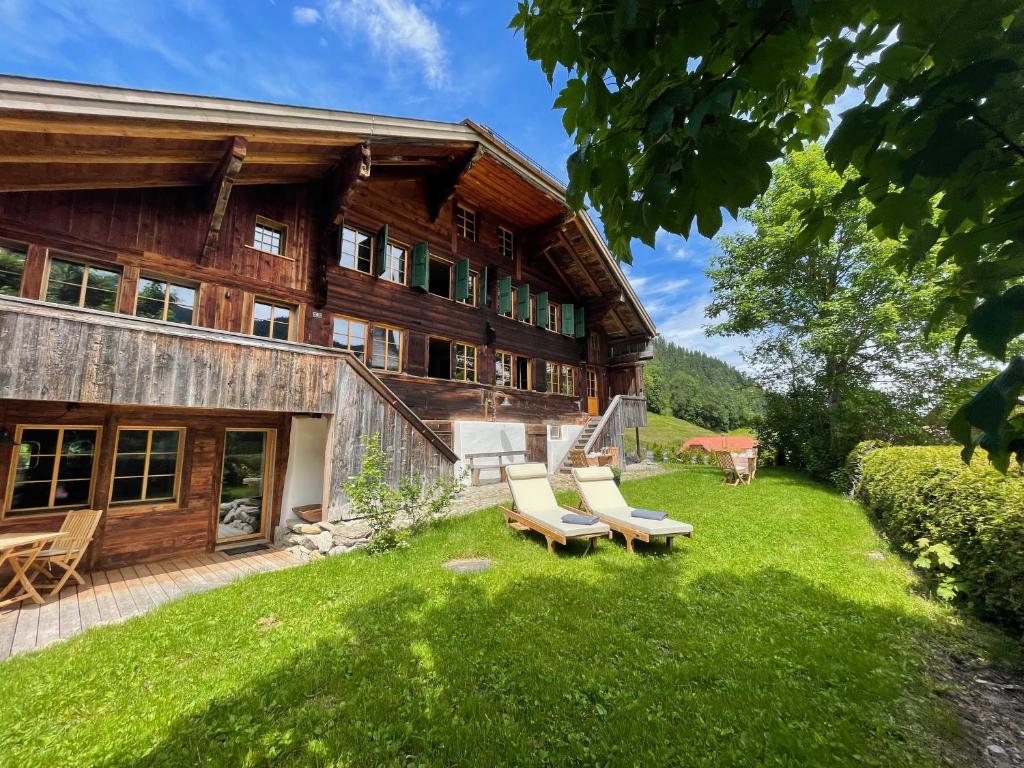 uma casa com espreguiçadeiras no quintal em Alpen Charme - Chalet d'Hôtes et SPA em Gsteig