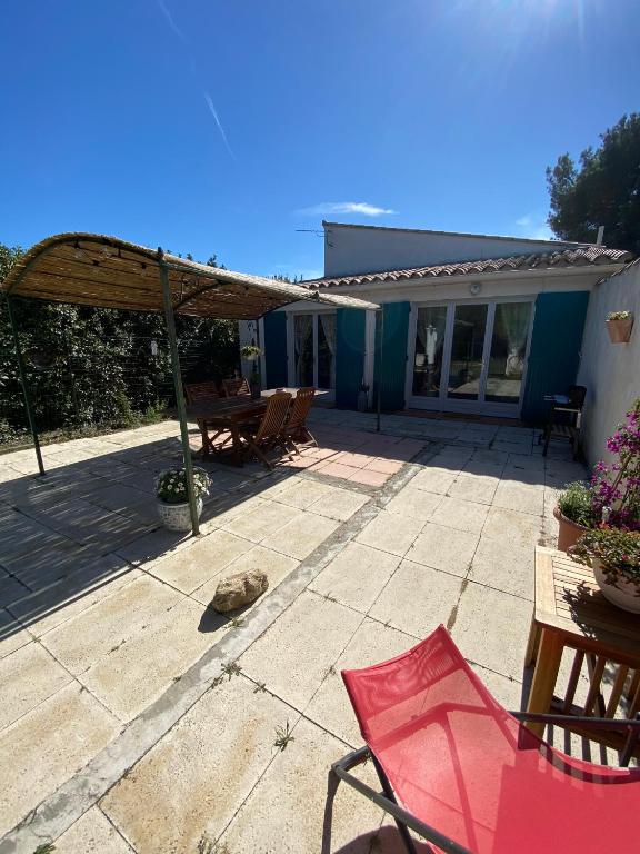 une terrasse avec une chaise rouge et un parasol en bois dans l'établissement Gîte Lou Gardian, à Aureille