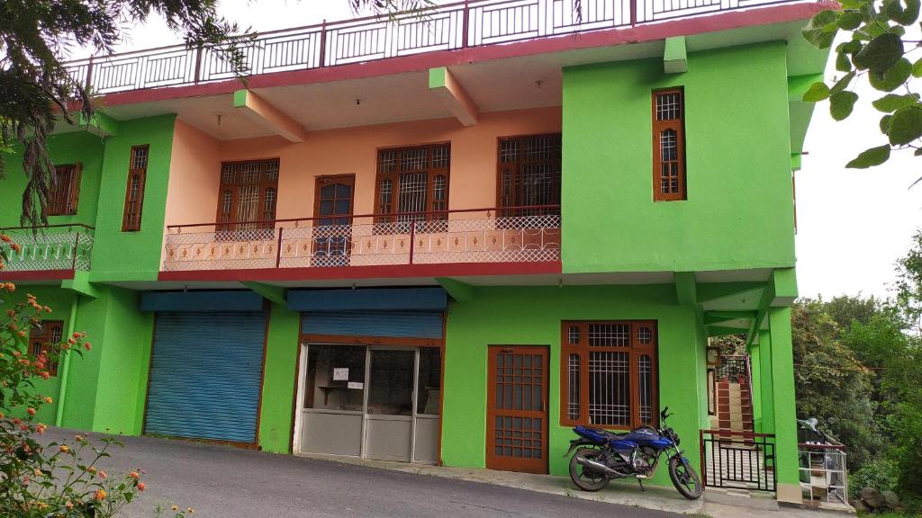 a green building with a motorcycle parked in front of it at Kanta riverside Home stay in Pālampur