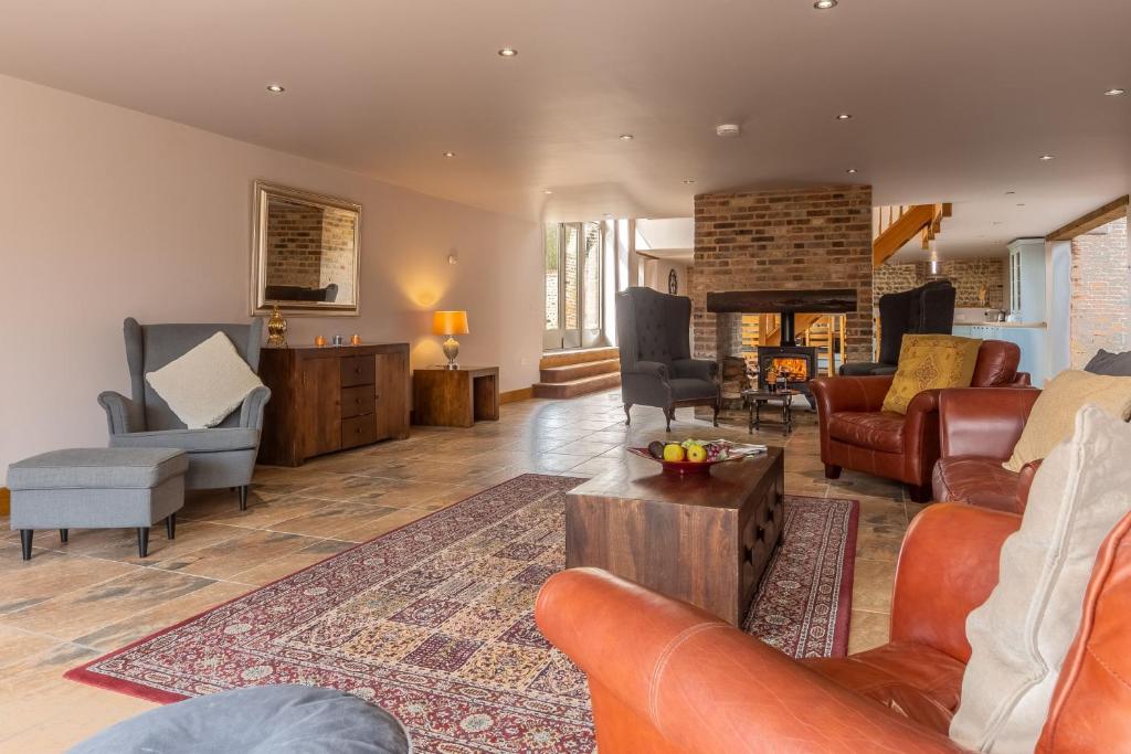 uma sala de estar com mobiliário de couro e uma lareira em The Old English Barn em Bacton