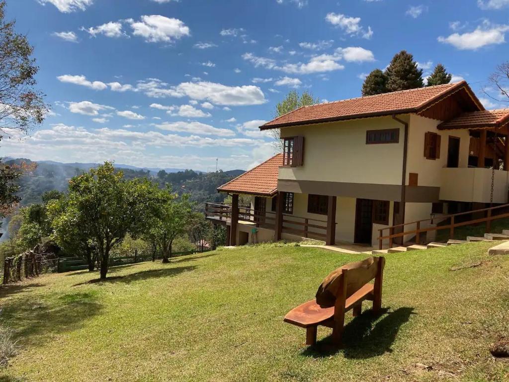 a bench sitting in the grass in front of a house at Chalé Recanto Bela Vista in Monte Verde