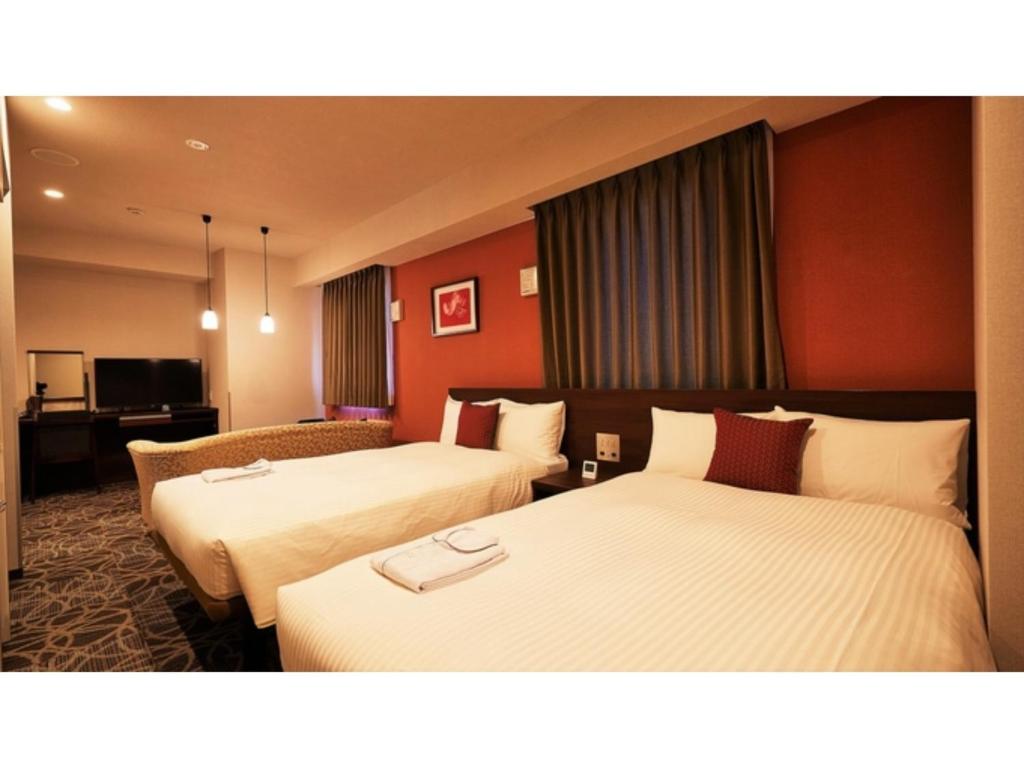 Y's Inn Naha Oroku Ekimae - Vacation STAY 25859v في ناها: سريرين في غرفة الفندق بجدران حمراء