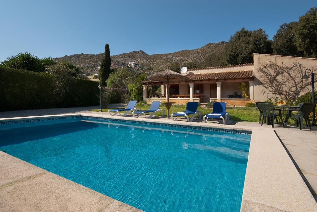 een zwembad met blauwe stoelen en een huis bij Villa Geroni in Pollença