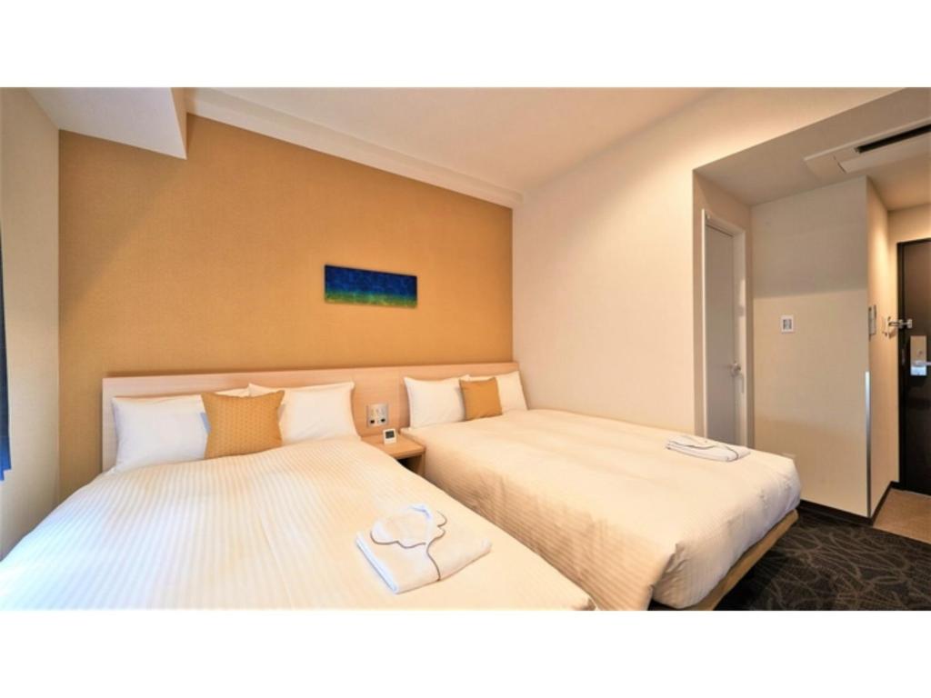 a hotel room with two beds with towels on them at Y's Inn Naha Oroku Ekimae - Vacation STAY 25852v in Naha