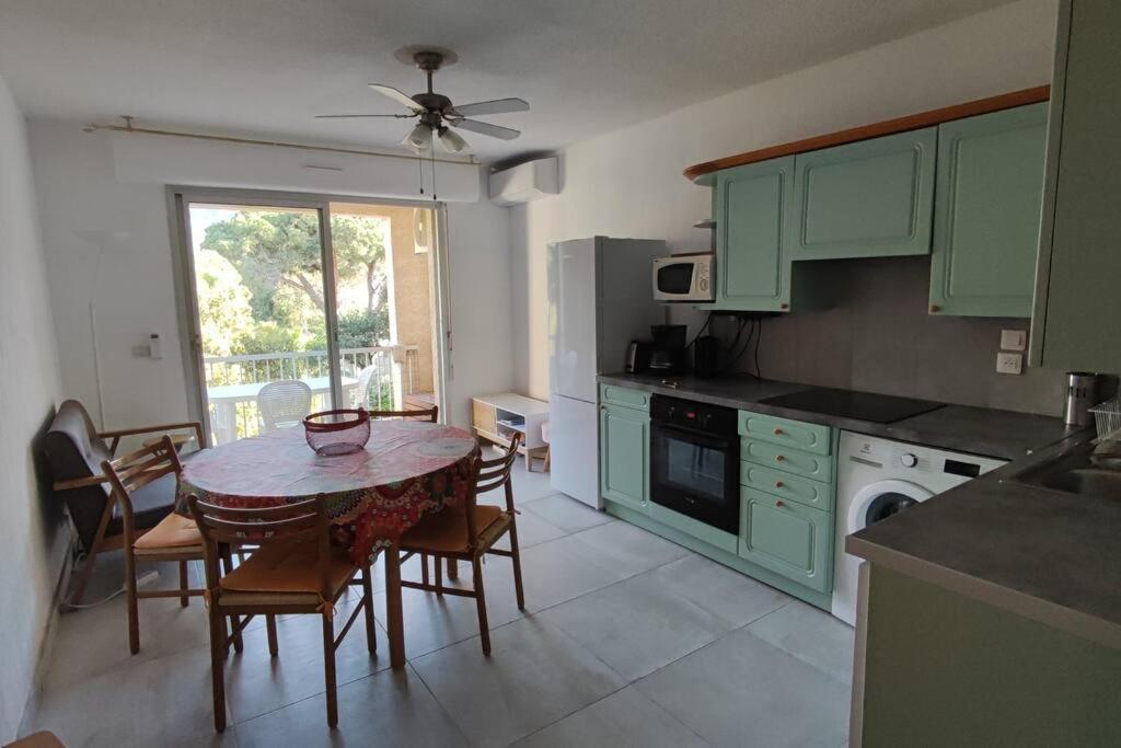 une cuisine avec des armoires vertes et une table et des chaises dans l'établissement Calvi T3 climatisé 150 m plage, à Calvi