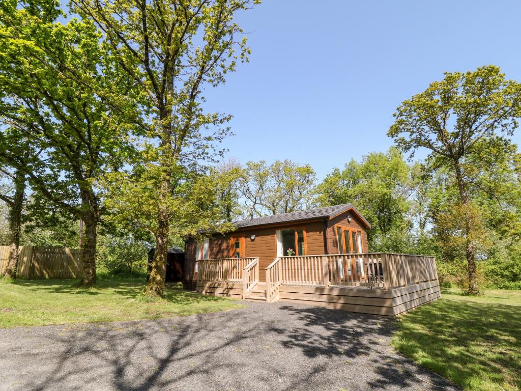 a small cabin with a large porch in a park at Dove Lodge in Beaworthy