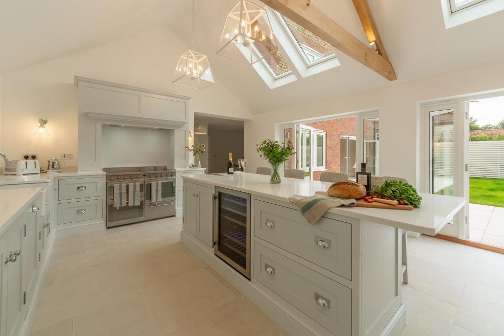 a large kitchen with white cabinets and white appliances at Limestone House in Burnham Market