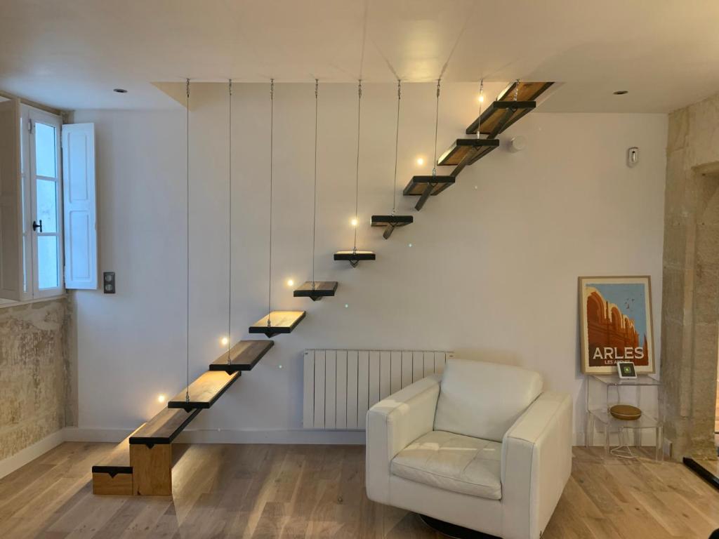 a living room with a white chair and a staircase at Superbe appartement avec vue in Arles
