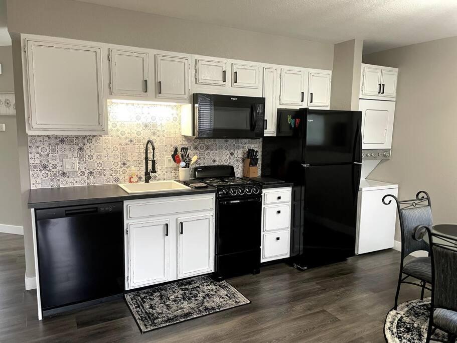 New Remodeled Luxury Condo By The Lake, No Stairs! في برانسون: مطبخ مع ثلاجة سوداء ودواليب بيضاء